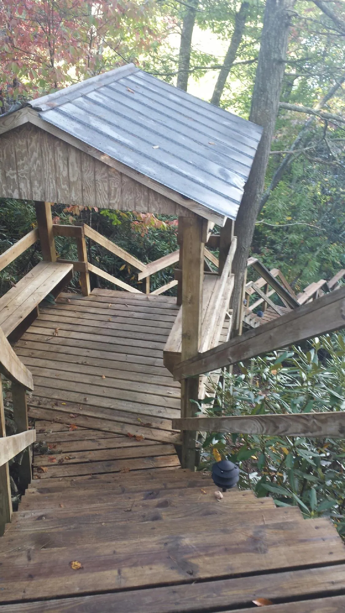 Metal roofed shelter over wooden steps on a wooded walkway — Skylight Repair & Installation work by our crew in Rice