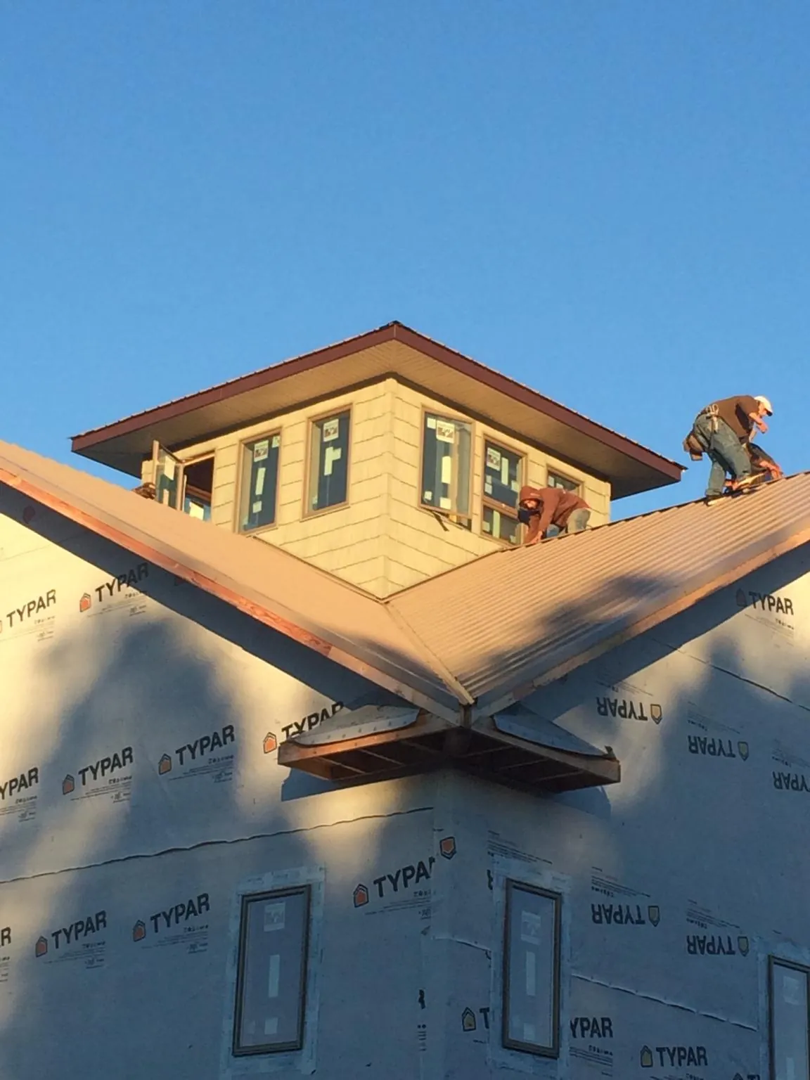 Roofers working around a rooftop cupola on a new metal roof at sunset — Roof Waterproofing in Rice by Roofing Brothers